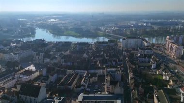 Terracotta çatıları üzerinde süzülen hava perspektifi ve sabahları sisli nehrin yanında yükselen katedral kulesi olan çağdaş binalar. 