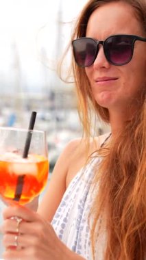 Marina Kafe İspanya 'da güneş gözlüklü bir kadın portakal kokteyli içiyor.