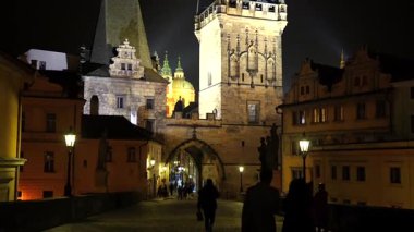 Prag 'daki Küçük Şehir Köprüsü' nün ışıldayan kemerine doğru yürüyorum. Tarihi binalar ve fenerlerin çerçevelediği yol altın akşam ışığıyla yıkanmış.