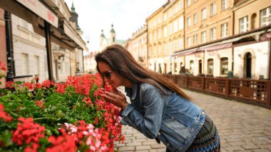 Genç kadın eski Avrupa şehrinde yaz çiçeklerinin tadını çıkarıyor.