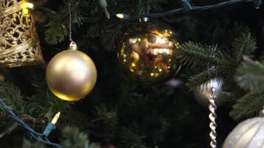 Altın Noel süslerini yakın ve sıcak ışıklarla süsleyin. Sıcak bir tatil ortamı yaratın.