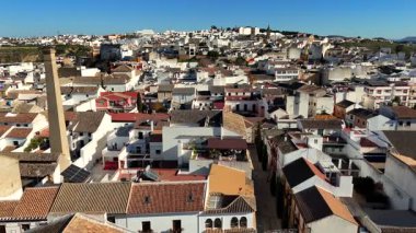 Puente Genil Endülüs İspanya 'nın insansız hava görüntüsü açık mavi gökyüzünün altındaki beyaz evler kilise kulelerini gösteriyor