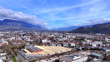 Endüstriyel çatıları, mavi gökyüzünde yeşil tepeleri olan Grenoble Fransa 'nın insansız hava aracı panoraması