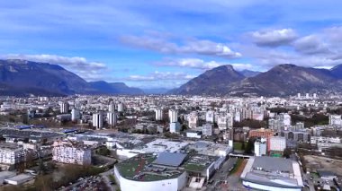 Mavi gökyüzünün altındaki kuleler ve Alpler ile Grenoble şehir manzarasının yüksek açılı drone görüntüsü