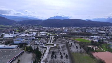 Endüstriyel binalarla otoyol kavşağının insansız hava aracı görüntüsü yeşil tepeler ve bulutlar
