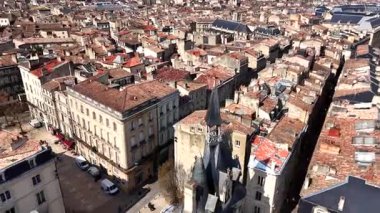 Sivri kuleleri, dar taştan caddeleri ve güneşli bir bahar gününde kafeleri olan küçük meydanı olan tarihi Bordeaux şehir merkezine insansız hava aracı videosu.