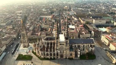 Tarihi Bordeaux şehir merkezinin insansız hava aracı görüntüsü. Katedral ve çan kulesi sisli altın saat ufkuna uzanıyor.