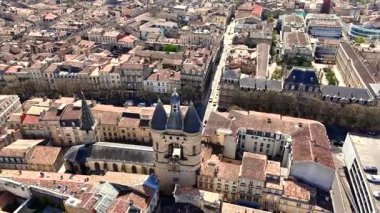 Grosse Cloche çan kulesinin insansız hava aracı videosu taş binaların üzerinde yükseliyor, çatılar döşenmiş ve Bordeaux 'nun dar sokakları aydınlık bir bahar gününde
