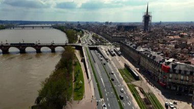 Bordeaux Pont de Pierre köprüsünün tramvaylar ve dramatik bulutlu gökyüzü üzerindeki insansız hava aracı görüntüleri.