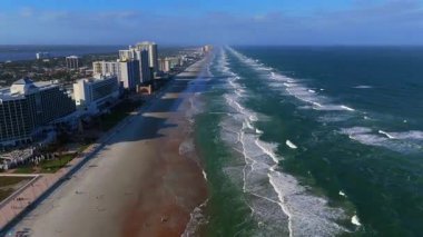 Güneşli bir günde, kumlu sahil dalgaları ve kıyı şehri ufkuyla Daytona Sahili Florida sahil şeridinin insansız hava aracı görüntüsü