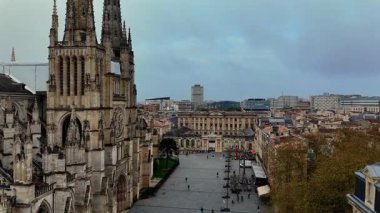 Bordeaux Saint-Andre Katedrali 'nin insansız hava aracı videosu ve modern ufuk çizgisi ufukta görünen tarihi merkezi yumuşak bulutlu gökyüzünün altında.