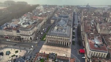 Bordeaux Büyük Tiyatrosu 'nun etrafındaki dinamik 4K insansız hava aracı yörüngesi trafik ve Quinconces ağaçlarını gösteriyor.