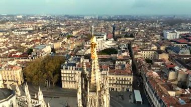 Altın Bakire Meryem heykelinin robot resmi Pey Berland Kulesi 'nin tepesinde düz caddeye, tramvay raylarına ve tarihi şehir çatılarına bakıyor.