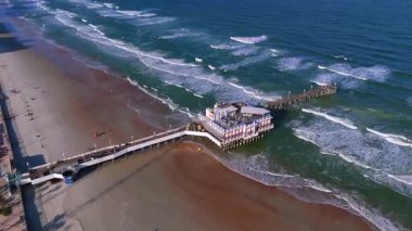 Daytona Sahili 'nin kıyı şeridi üzerinde açık havada okyanus dalgaları ve kumlu kumsalla kaplı.