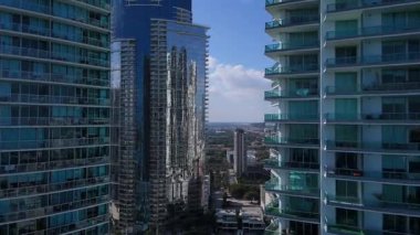 Miami şehir merkezindeki yüksek modern binalarda insansız hava aracı uçuşu yoğun şehir mimarisini ve hızla büyüyen metropol şehrini gösteriyor.