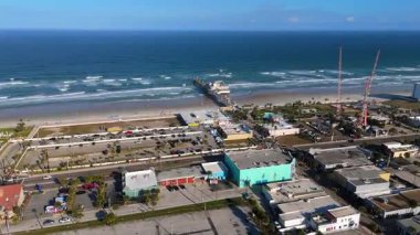 Güneşli bir günde, uzun okyanus rıhtımı, kumlu kıyılar ve Atlantik dalgalarıyla Daytona Sahili üzerindeki insansız hava aracı görüntüsü.