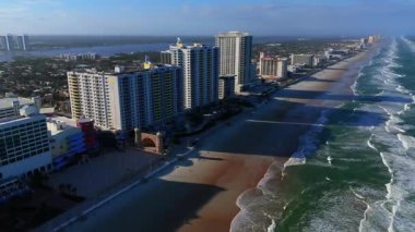 Daytona Sahili Florida 'nın insansız hava aracı görüntüsü açık gün ışığında kumlu kıyısı ve Atlantik Okyanusu olan modern yüksek binalara ev sahipliği yapıyor.