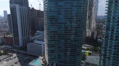 Miami şehir merkezindeki modern cam gökdelen. Gündüz çekilmiş. Yüksek binalı mimari, yoğun kentsel çevre ve çağdaş şehir gelişimi sergileniyor..