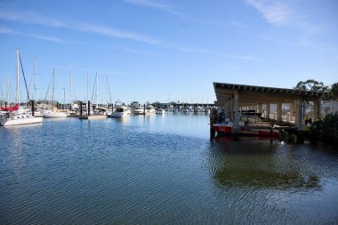 Yatlı sakin liman manzarası ve mavi gökyüzünün altında modern bir liman manzarası.