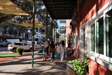 3 Ocak 2026 'da Saint Petersburg Florida' da kırmızı binanın ve açık hava dekorunun önünden geçen insanların olduğu şehir caddesi.