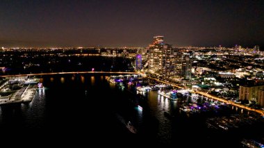 Gece vakti yüksek binalar ve rıhtımlarla parlayan şehir silüeti