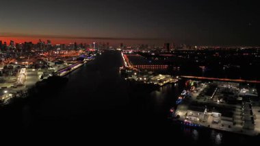 Miami limanındaki vinçlerin ve şehrin insansız hava aracı antenleri günbatımı gökyüzünün altında
