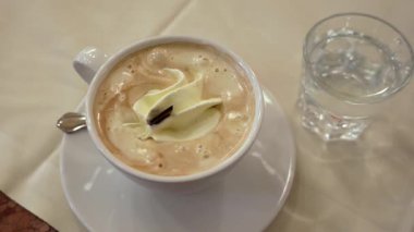 Kapuçino ve bir bardak su zarif masa ayarı üzerinde yakın plan.