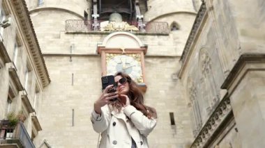 Bordeaux şehir merkezindeki tarihi saat kulesinde kadın selfie çekiyor.