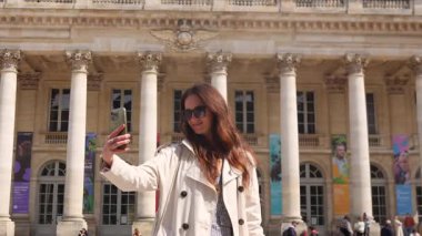 28 Mart 2025 Bordeaux France gülümseyen kadın sadece gündüz vakti neoklasik sütunlu bina tarafından selfie çekiyor.