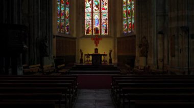 Katedral sunağı boyalı cam pencereler ve düşük ışıkta gotik kemerler ile çerçevelenmiştir.