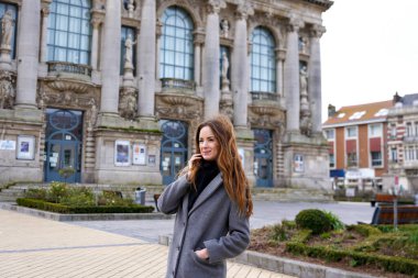 Calais Fransa 'da tarihi tiyatro binasının yakınında poz veren şık bir kadın.