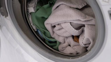 Yıkanmadan önce havlu ve giysileri gösteren bir çamaşır makinesinin içindeki gerçek yakın plan çamaşırları. Gerçek hayat konsepti ev işleri, çamaşır bakımı ve sürdürülebilir ev işleri. Ev hayatını, tekstil bakımını ve her şeyi göstermek için mükemmel.