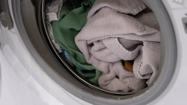 Yıkanmadan önce havlu ve giysileri gösteren bir çamaşır makinesinin içindeki gerçek yakın plan çamaşırları. Gerçek hayat konsepti ev işleri, çamaşır bakımı ve sürdürülebilir ev işleri. Ev hayatını, tekstil bakımını ve her şeyi göstermek için mükemmel.