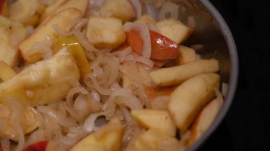 Tavada pişirilen doğranmış elma ve soğanların yakın çekimi. Görüntü, ev yapımı turşu, çeşni ya da sosta kullanılan doğal dokuları ve renkleri gösteriyor. Tarifler, yemek hazırlama, sağlıklı beslenme, fermantasyon ya da