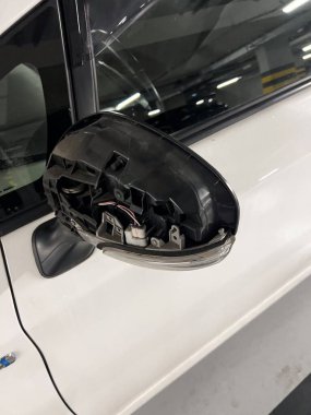 Görünür iç hatları olan kırık bir araba yan aynasının yakın görüntüsü, yeraltı otoparkında çekilmiş. Gerçekçi görüntü küçük araba kazalarını, vandalizmi ve araç tamir sorunlarını sembolize ediyor. Sigorta tazminatı, hasar değerlendirmesi, 