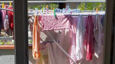 Parlak yaz sahnesi. Renkli giysiler, güneş ışığında balkonda asılıydı. Günlük ev hayatına gerçekçi bir bakış açısı ve çevre dostu kurutma metodu. Evde bakım, aile hayatı ve sürdürülebilir yaşam için elverişli, 