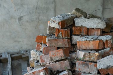Bitmemiş ya da terk edilmiş bir binanın içinde beton parçalarıyla karıştırılmış eski kırmızı tuğla yığını. Görüntü inşaat atıkları, yıkım malzemeleri, yenileme süreci veya yeniden inşa aşamasını temsil ediyor