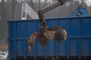 Metal geri dönüşüm tesisinde hidrolik bir vince tutturulmuş ağır dişli pençeyi kapat. Kış koşullarında hurda ve malzeme taşımak için kullanılan endüstriyel ekipmanlar. Uygun.