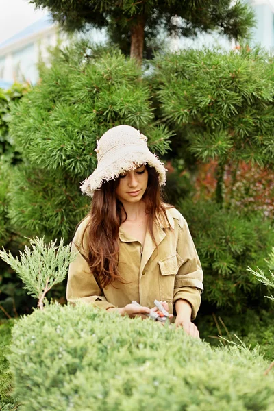 Дівчина садівник в робочому одязі і солом'яному капелюсі вирізає садові ножиці — стокове фото