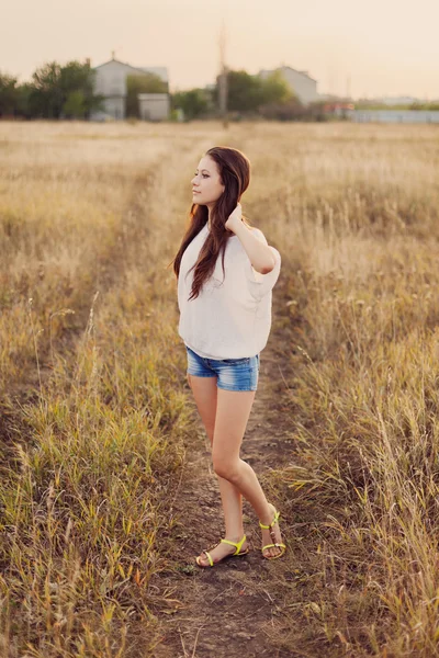 Chica joven con el pelo castaño largo estancia en el prado — Foto de Stock