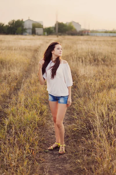 Chica joven con el pelo castaño largo estancia en el prado — Foto de Stock