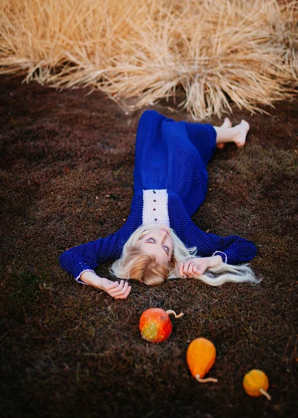 Жінка, одягнена в синю вінтажну сукню, лежить в осінньому парку . — стокове фото