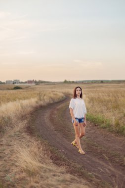 Alanında yol boyunca yürüyüş uzun kahverengi saçlı genç kız