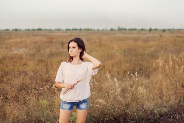 Uzun kahverengi saçlı ayakta sonbahar çayır adlı genç kızla
