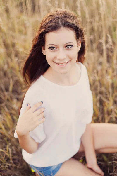 Hermosa joven morena en el prado de otoño sonriendo — Foto de Stock