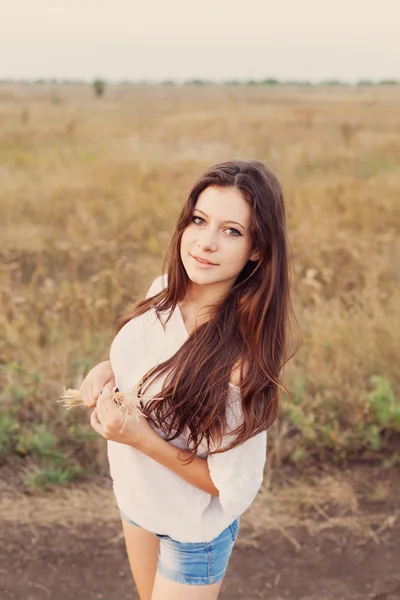 Chica joven con el pelo castaño largo sostiene un manojo de orejas — Foto de Stock