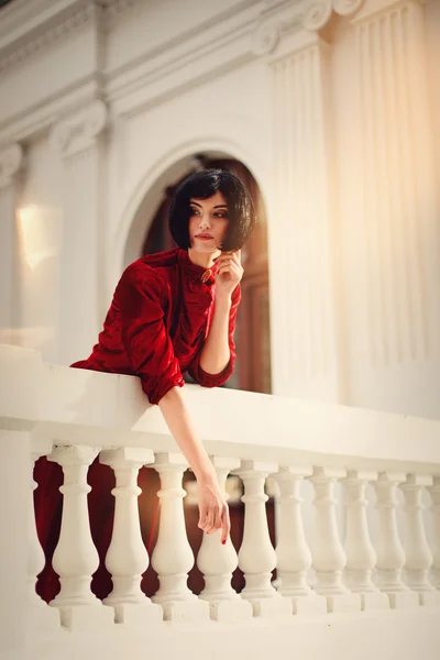 Hermosa mujer morena con vestido rojo, posando en un castillo — Foto de Stock