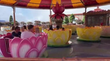 Ba Na Hills Vietnam eğlence parkında renkli dönen bardak gezintisi. Pembe sarı ve beyaz bardaklar eski ziyaretçileri döndürüyor. Eğlenceli karnaval atmosferi yaratıyor Da Nang Vietnam 10.27.2025