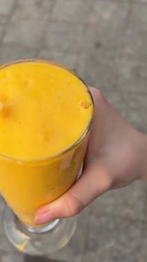 Mango Smoothie, Cafe Sea Island Dağı 'nın arka planına cam koydu. Ahşap tabakta mangolu yoğurt püresi. Vietnam Danang 10.29.2025