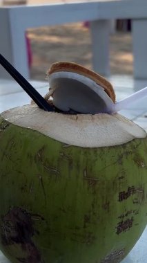 Ocean Beach 'te rahat bir kadının ellerinde alkolsüz kokteyl ile hindistan cevizi. Ferahlatıcı içkinin yakın çekimi, yaz günü sahilde dinlenen ve sakinliği hisseden çekici bir kadın..